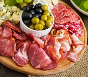 Antipasto catering platter with bacon jerky salami cheese grapes wooden table 300x262