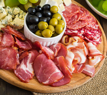 Antipasto catering platter with bacon jerky salami cheese grapes wooden table 360x320