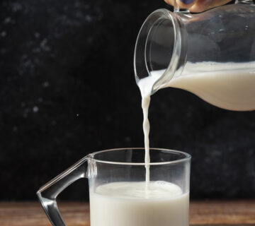 Woman pouring milk into glass mug wooden table 360x320